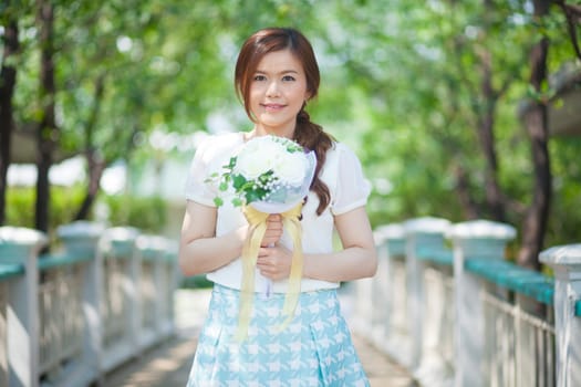 Young asian cute woman smelling white flowers