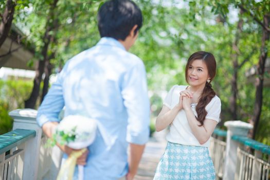 Man ready to give flowers to girlfriend in the park