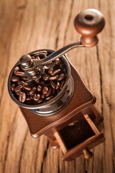 Vintage manual coffee grinder with coffee beans on wood table