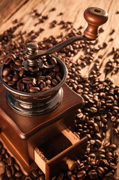 Vintage manual coffee grinder with coffee beans on wood table