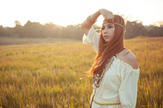 Hippie woman posing in golden field on sunset