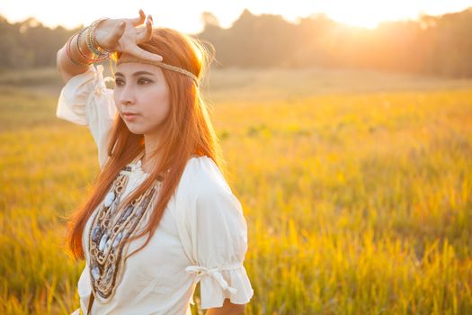 Hippie woman posing in golden field on sunset