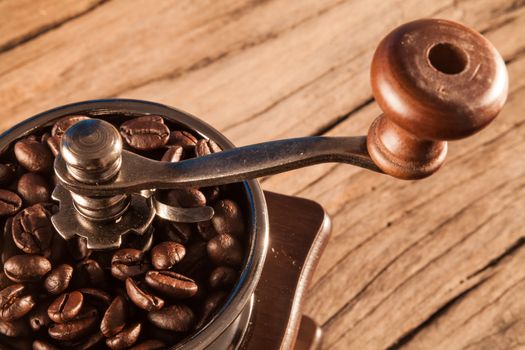 Vintage manual coffee grinder with coffee beans on wood table