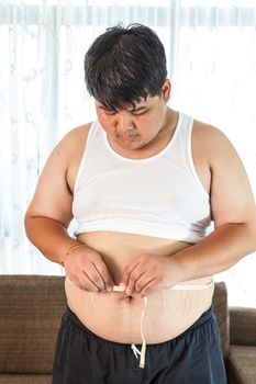 Asian Fat man holding a measuring tape in house