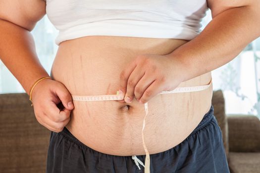 Asian Fat man holding a measuring tape in house