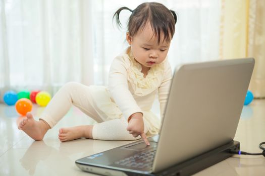 Portrait of little asian girl play laptop in home