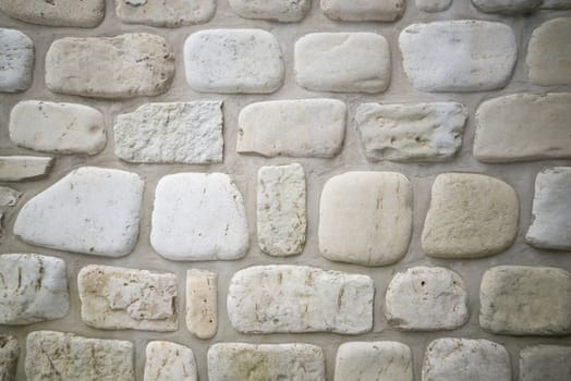 Old stone wall background with rounded limestone cobbles in the wall of a waterfront cottage on georgian bay. Has cement mortar between.