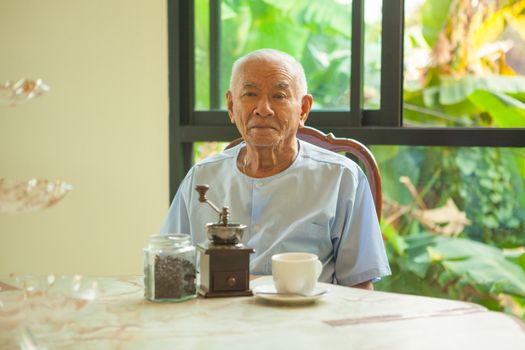 Asian senior man with vintage coffee grinder