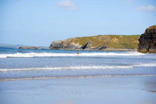 bright winter view of kayaker at ballybunion beach and cliffs on the wild atlantic way in ireland