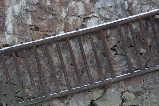 Old wooden ladder on a stone wall