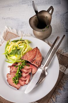 Zucchini pasta and meat with a sauce on a table