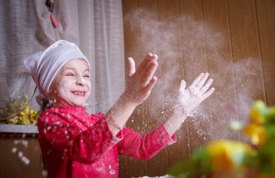 Happy girl playing with flour in kitchen