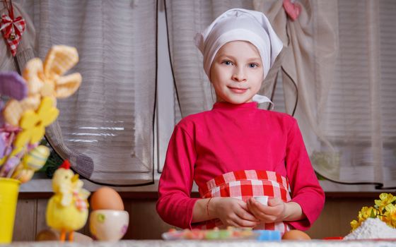 Cute girl in apron making easter cookies in kitchen