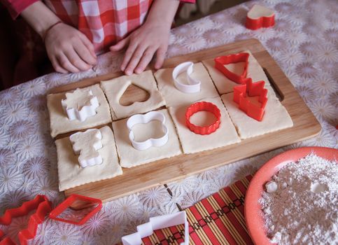 Girl hands making biscuits from dough in kitchen