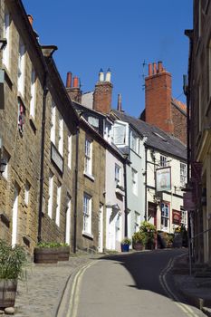 Steep narrow street with houses on either side in Robin Hoods Bay, near the coast of North Yorkshire, England.