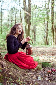 mystical witch woman sitting and holding a lantern in the forest