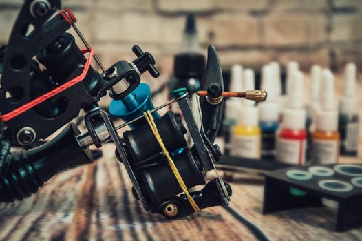 Tattoo machine and tattoo supplies on wooden background
