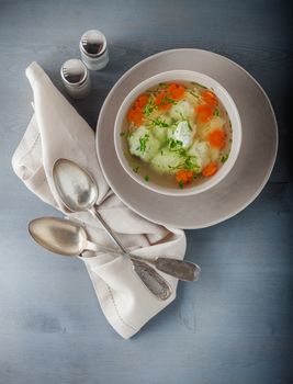 Chicken soup with meatballs and vegetables on a table