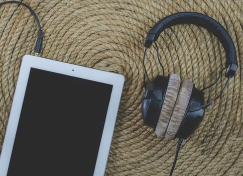 tablet and headphone music  on a jute rope background