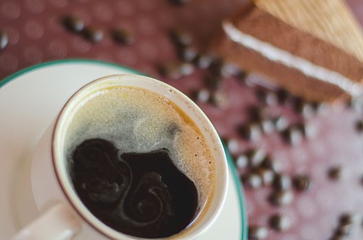 A cup of coffee with slice of chocolate cake on tray background