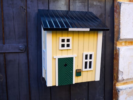Creative colorful mailbox shaped like a house on a wooden door