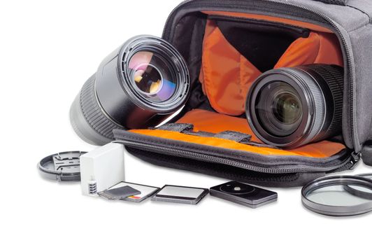 Fragment of the open camera bag with two different photo lenses closeup and some photo accessories in the foreground on a light background
