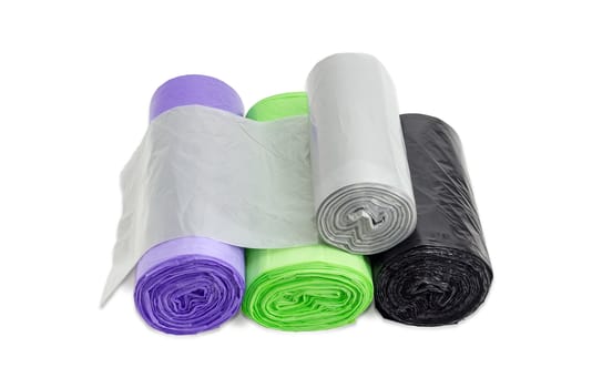 Several plastic disposable garbage bags of different sizes and colors in rolls including biodegradable and with handles which may be tied on a light background
