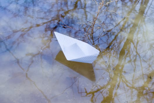 Toy paper boat made of squared paper in the puddle of a melt water
