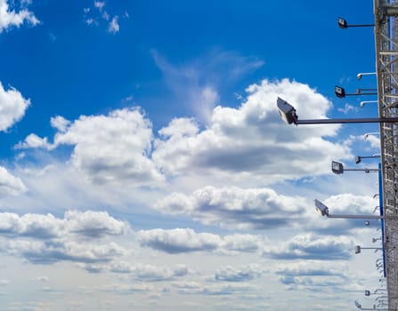 Many light fixtures for billboard backlighting against the background of sky with clouds in daytime
