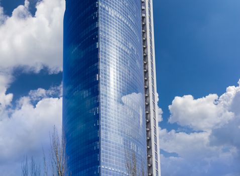Fragment of building of a large modern multistory office center against the background of sky with clouds
