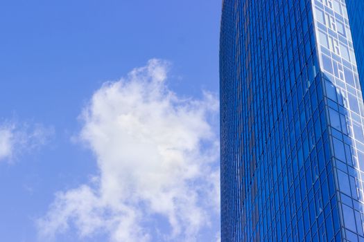 Fragment of the large modern multistory office building against the background of sky with cloud

