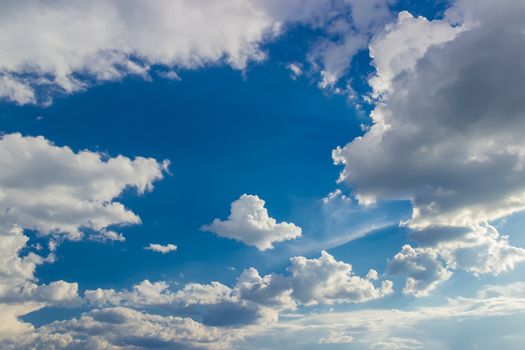 Background of the sky with cumulus clouds with sun rays from behind the cloud in a spring day
