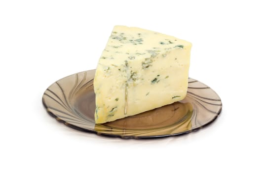 Piece of crumbly blue cheese made of a sheep milk on the dark-colored glass saucer closeup on a light background
