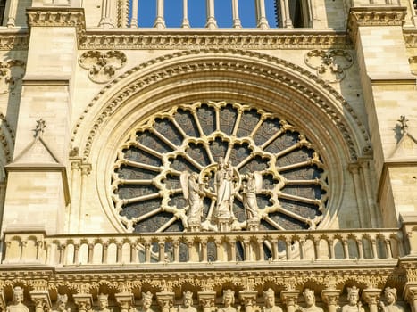 Exterior of the rose window on a western facade of the Cathedrale Notre-Dame de Paris with a sculpture of the Virgin Mary with Jesus and Old Testament characters

