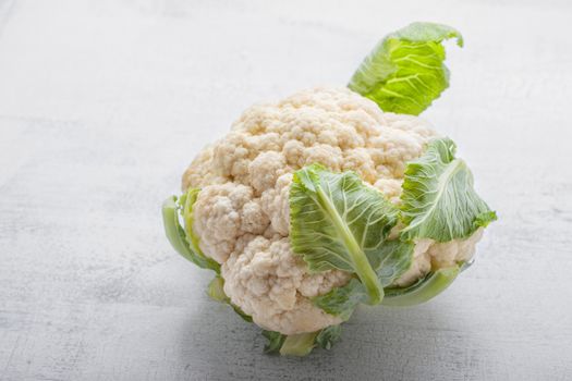 A head of Fresh Cauliflower on a white surface