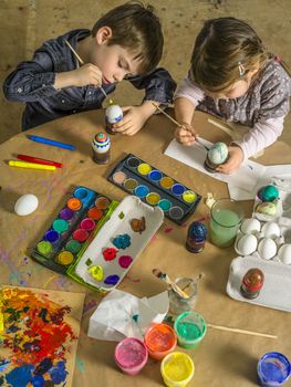 Photo of a brother and sister painting and decorating hard-boiled eggs for easter.