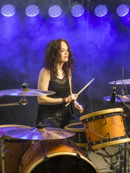 Photo of a beautiful woman playing her drum set on stage.