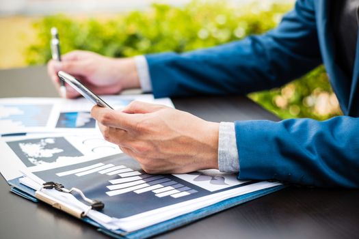 Handsome businessman wearing suit and using modern laptop outdoors and graph finance diagram