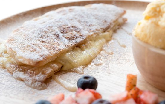 fresh dessert soft vanila roti with ice cream ,syrup ,strawberry and blueberry on plate in restaurant ,selective focus