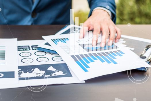 Handsome businessman wearing suit and using modern laptop outdoors and graph finance diagram.