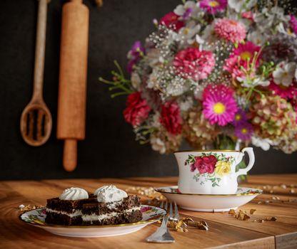 Closeup of cup of tea with cake and flowers bouquet on the wood table close up photo