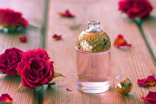 perfume bottle and pink roses on wooden table
