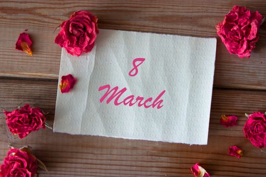 note and dry pink roses on wooden table