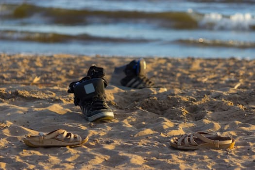 black sneakers with sea wave on sand background