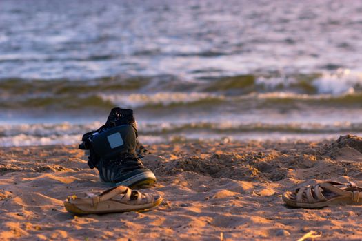 black sneakers with sea wave on sand background