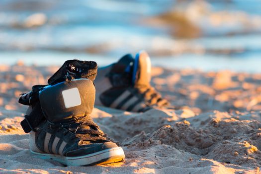 black sneakers with sea wave on sand background