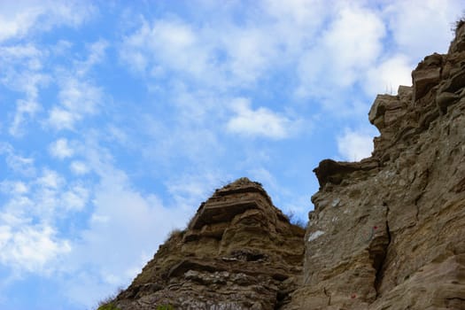 textured rock wall against a blue sky.