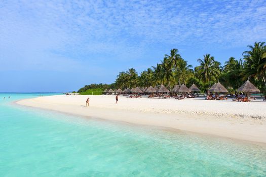 bungalows on a white beach with coconut palms on Maldives Island