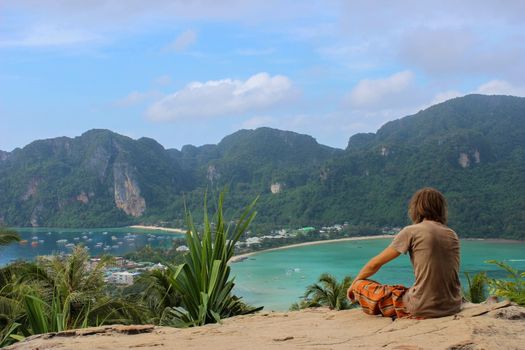 a young man sitting in yoga lotus pose meditation outdoors. Phi Phi Don Island, Thailand