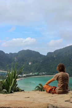 a young man sitting in yoga lotus pose meditation outdoors. Phi Phi Don Island, Thailand